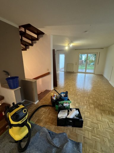 Leerer Raum mit Treppe, Teppich und Reinigungsgeräten.